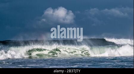 Seascape. Powerful ocean wave on the surface of the ocean. Wave breaks on a shallow bank. Stormy weather, stormy clouds sky background. Stock Photo