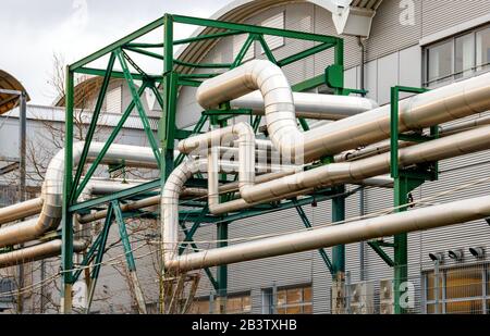 Complex pipeline of a power plant. Multiple aluminium pipes entangled with each other and supported by a green metal frame. Stock Photo