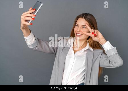 Young business woman studio isolated on gray taking selfie pictures happy Stock Photo