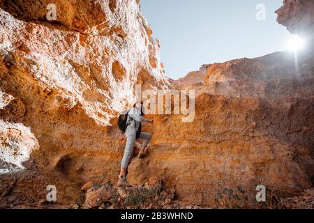 Female traveler climbing on the huge rock volcanic origin on a sunny day. Traveling on Tenerife island, Spain Stock Photo