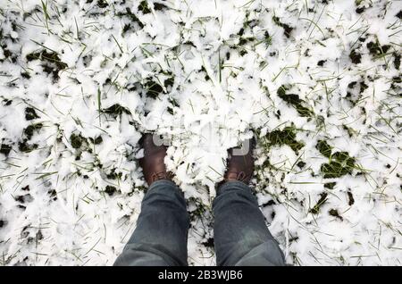 Male feet stand in fresh snow, top view photo, winter walking theme