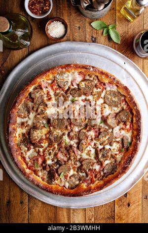 Deep dish meat pizza on a wooden table Stock Photo