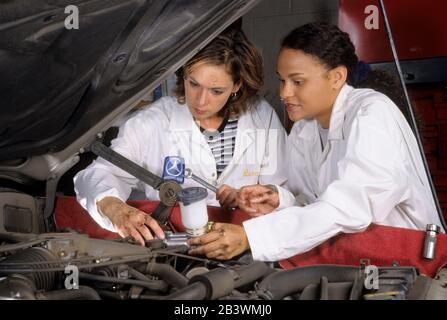 Austin Texas USA, 1999: Female Hispanic and Black auto mechanics  install master brake cylinder in Toyota in automotive repair shop  MR ©Bob Daemmrich Stock Photo