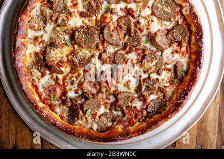 Deep dish meat pizza on a wooden table Stock Photo