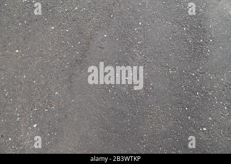 Wet asphalt texture, rough texture with cracks and dents. Stock hoto for web and print, background and wallpaper with empty space for text and design. Stock Photo