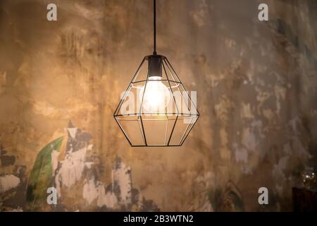 Industrial style wire lamps with filaments glowing inside glass light bulbs in darkness. Shiny lights and dark background. Urban style interior Stock Photo