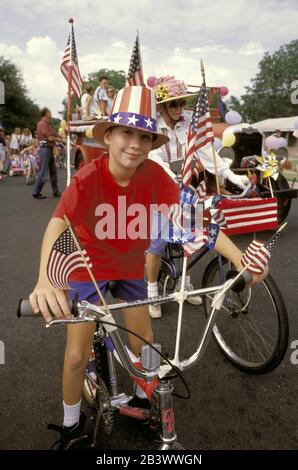 Austin, Texas: Boy wearing Uncle Sam top hat and riding bicycle with American flags on it during annual Fourth of July celebration parade in his neighborhood. ©Bob Daemmrich Stock Photo