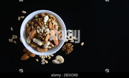 superfood concept, almond, cedar, walnuts, cashew nuts in a plate on a black background Stock Photo
