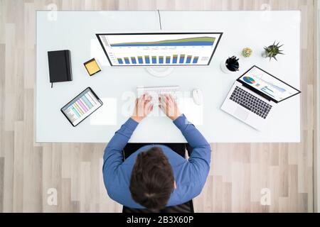 High Angle View Of Young Businessman Working With Graphs On Computer Stock Photo