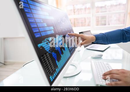 Young Businessman Analyzing Graphs On Computer At Office Stock Photo