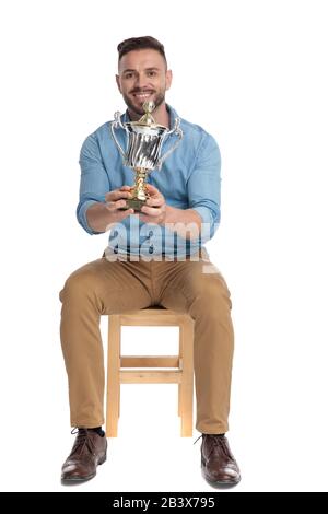 seated casual man holding his trophy in the air on white background ...