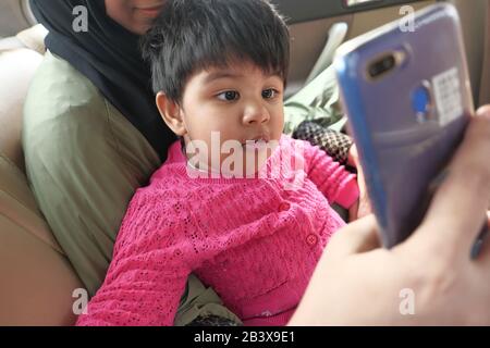 Close up of mother and baby child taking selfies in a car  Stock Photo