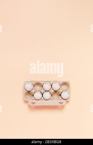 Happy Easter. White eggs with painted eyes in paper packaging on pink background. Flat lay, top view, copy space. Stock Photo