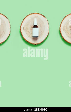Zero waste concept. Glass reusable bottle for natural oil, perfume or deodorant located on a wooden cut, tray. Flat lay, top view, copy space. Stock Photo