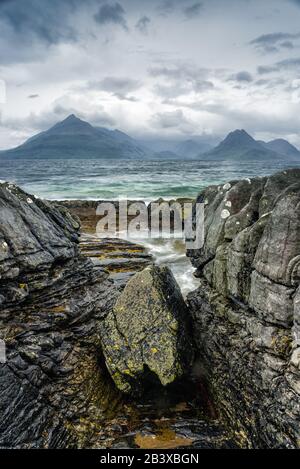 A Summer storm passes over the Cuilin Mountains and sea as seen from the rocky coast of Elgol, Isle Of Skye, Scotland Stock Photo