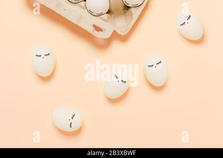 Happy Easter. White eggs with painted eyes in paper packaging on yellow background. Stock Photo