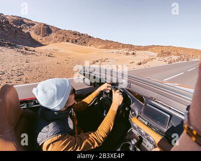 Man driving convertible car while travel on the desert road. Image made on mobile phone Stock Photo