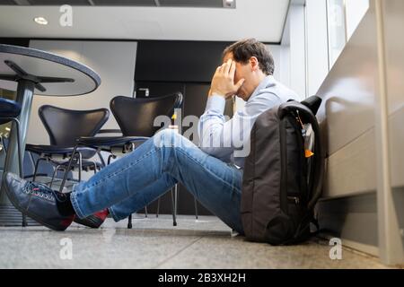 Flight Delay And Cancellation. Upset Man In Airport. Stock Photo