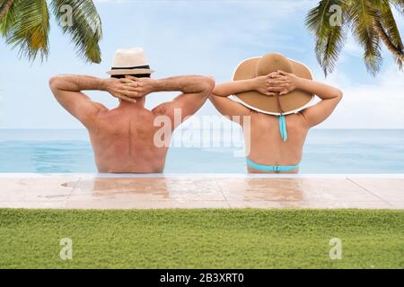 Couple In Infinite Swimming Pool With Palm Trees In Background Stock Photo