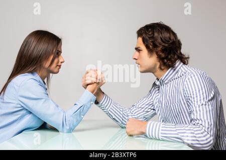 Husband and wife are fighting in their arms, arm wrestling between male and female. Family quarrel, showdown, division of property, divorce. Stock Photo
