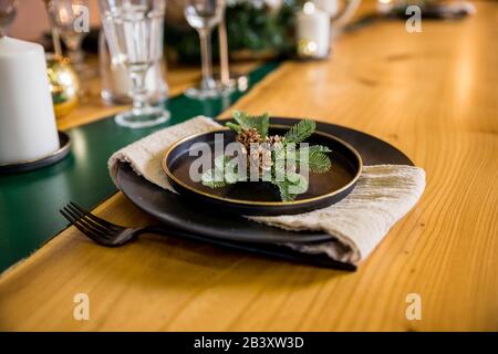 Christmas table setting. Black tableware and decoration with fir-tree branch. Flat lay, top view.Happy New Years Eve elegant dinner table setting with Stock Photo