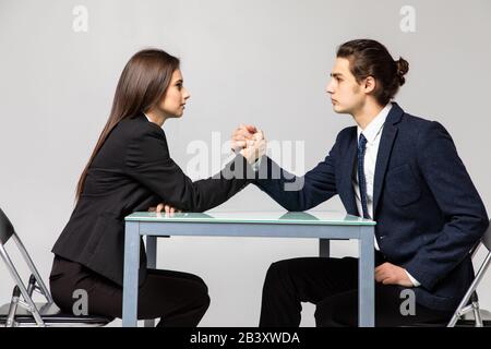 Business couple are fighting in their arms, arm wrestling between male and female. Family quarrel, showdown, division of property, divorce. Stock Photo