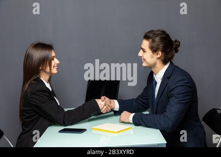 Friendly smiling businessman and businesswoman handshaking over the office desk after pleasant talk and effective negotiation, good relationship, maki Stock Photo