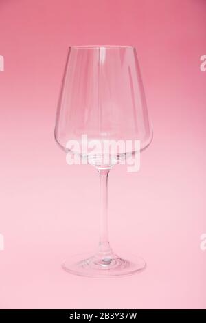 Empty wine glass which stands on a pink background. Stock Photo