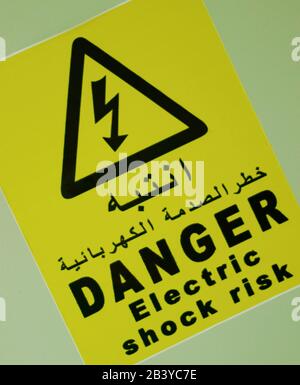 electric shock risk, danger sign board label in black letter in Arabic letter also with yellow background Stock Photo