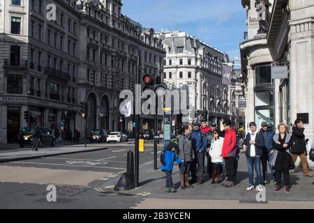London, UK - 20 February, 2020, People waiting for the green light at a pedestrian crossing in Regent Street Stock Photo
