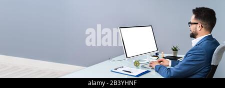 Close-up Of A Businessman Using Computer With Blank Screen At Workplace Stock Photo