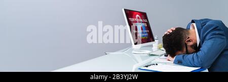 Worried Businessman Near Computer With Ransomware Word On The Screen At The Workplace Stock Photo