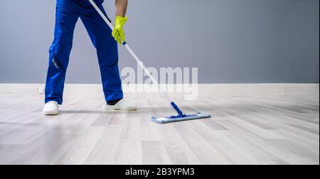 Worker Mopping Floor With Mop In Office Stock Photo