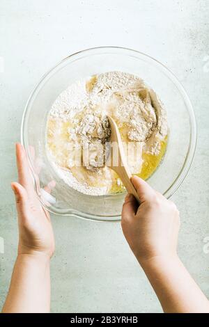 mixing dough for chocolate cake in a bowl. female hands and a kitchen whisk. recipe step by step Stock Photo