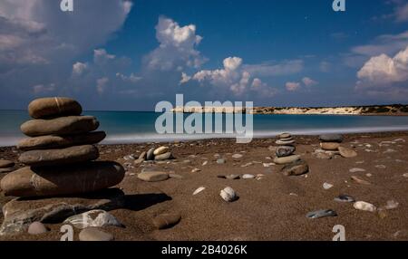 Pillars of stones on the sandy and pebble beach of the Mediterranean Sea, shot in calm weather at night with a long exposure. Stock Photo