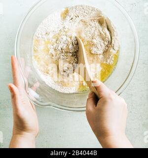 mixing dough for chocolate cake in a bowl. female hands and a kitchen whisk. recipe step by step Stock Photo