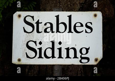 Stables Siding retro metal sign on a steel post under a shady tree Stock Photo