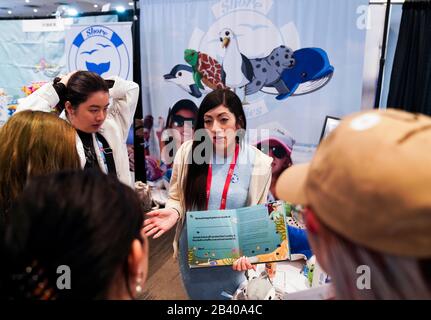 New York, USA. 25th Feb, 2020. A saleswoman of Shore Buddies talks with visitors at the company's booth at the 2020 Toy Fair New York in New York, the United States, on Feb. 25, 2020. Without his Chinese partner, it may not be easy for Malte Niebelschuetz to turn his inspiration of manufacturing plush toys from recycled bottles into reality. Credit: Wang Ying/Xinhua/Alamy Live News Stock Photo