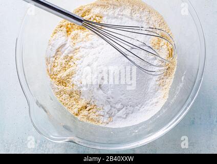 mixing dry ingredients in a glass bowl with a whisk Stock Photo