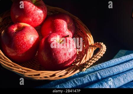 red apples in hand made basket with blue background Stock Photo