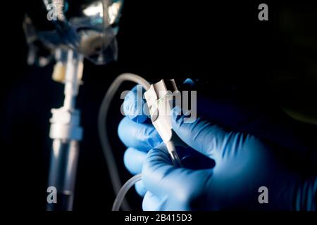 Nurse adjusts flow rate of IV drip medication from IV bag. Stock Photo