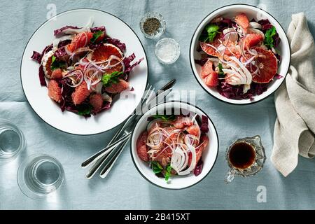 Sicilian salad with fennel, oranges, grapefruit and radicchio salad with balsamic dressing on a blue linen tablecloth. healthy summer italian food Stock Photo