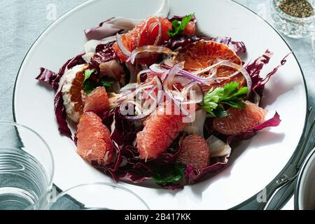 Sicilian salad with fennel, oranges, grapefruit and radicchio salad with balsamic dressing on a blue linen tablecloth. healthy summer italian food Stock Photo
