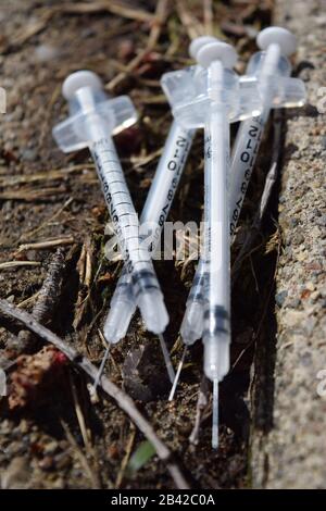 Used needles discarded in a public park. Opioid crisis pollution. Danger of contagious diseases Stock Photo