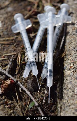 Used needles discarded in a public park. Opioid crisis pollution. Danger of contagious diseases Stock Photo