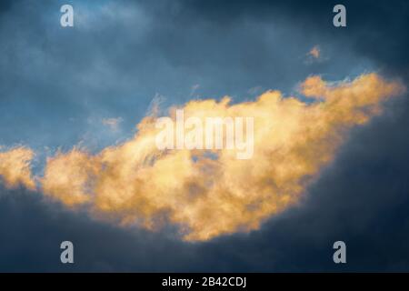 Amazing view natural meteorology background, fluffy thunderstorm clouds illuminated by disappearing rays at sunset and dark thunderclouds floating acr Stock Photo