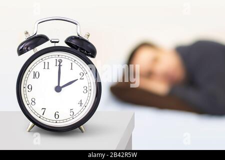Daylight Saving Time, Spring forward. A clock watch with person sleeping in the background. Stock Photo