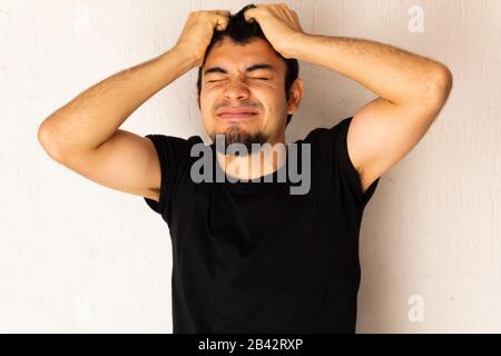 Young short-haired Hispanic man with black clothes, angry, furious, upset, stressed posing on a white background Stock Photo