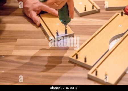 Side view and close up photo of carpenter person with professional electric screwdriver instrument in hand and repairing, fixing on building new Stock Photo