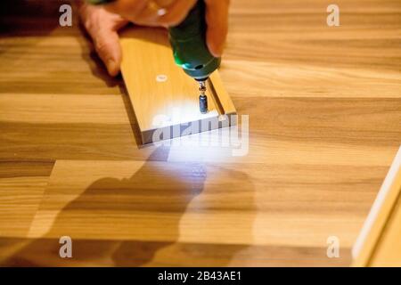 Wooden furniture assembling, woodworker screwing screws using a cordless Assembling furniture from chipboard, using a cordless screwdriver furniture Stock Photo